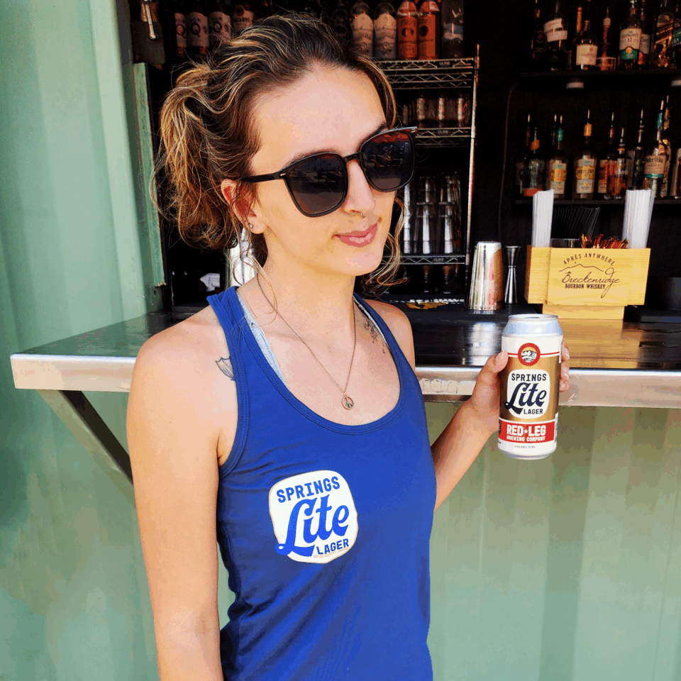 Woman holding Springs Lite can wearing a Springs Lite Blue Racerback tank top